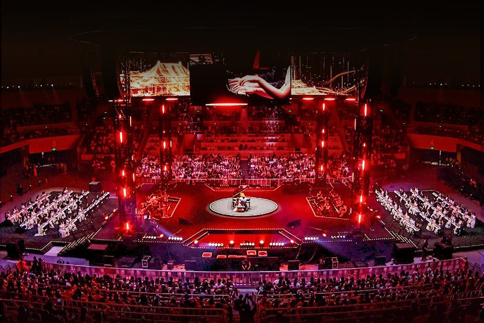 A red-lit concert arena with a central piano stage and young pianists performing on both sides