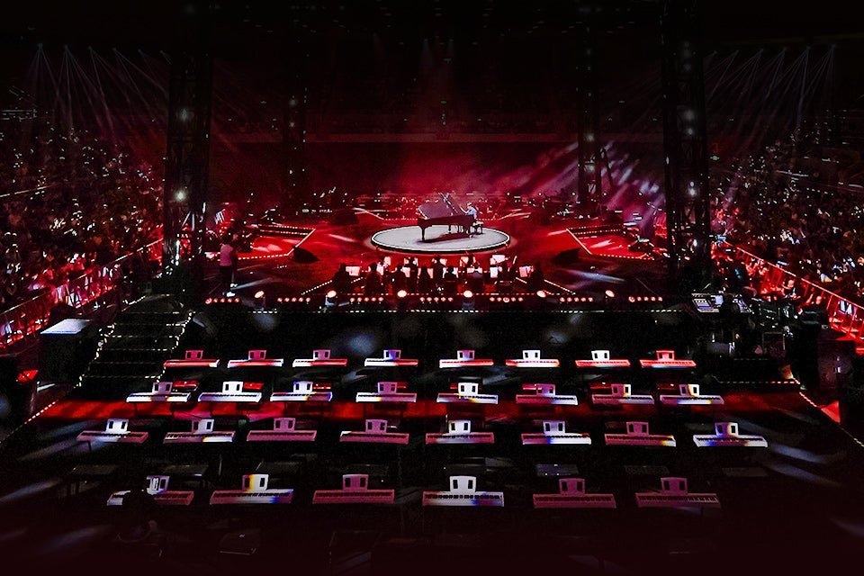 White TERENCE pianos arranged in front of the red-lit central concert stage