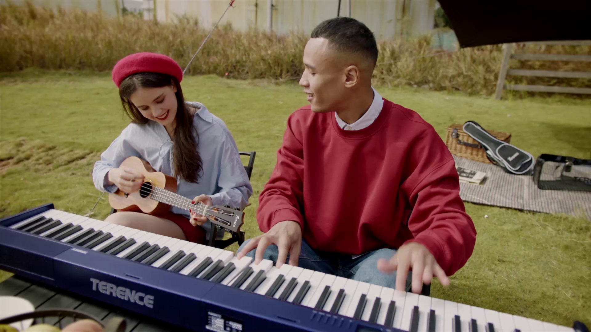 Two musicians playing a TERENCE digital piano and ukulele on the grass